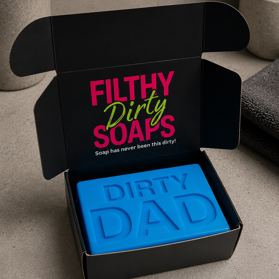 A black gift box with the words 'FILTHY Dirty SOAPS' printed inside, containing a bright blue bar of soap embossed with 'DIRTY DAD'. 