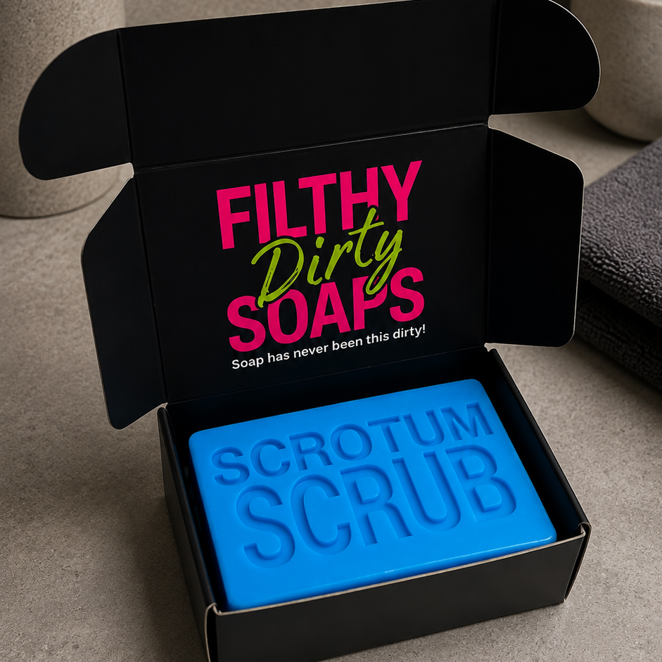 A bright blue bar of soap labeled 'SCROTUM SCRUB' sits inside an open black gift box with the text 'FILTHY Dirty SOAPS' printed on the inside lid. 