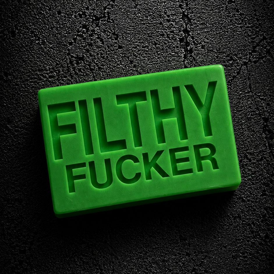 A bright green rectangular bar of soap with the words 'FILTHY FUCKER' embossed on the front, set against a dark textured background.